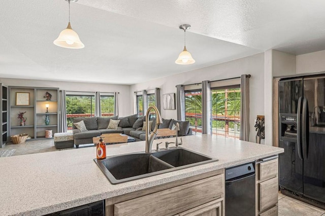 kitchen featuring light countertops, pendant lighting, black fridge, and a sink