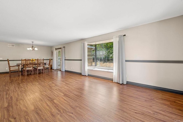 living room with baseboards, an inviting chandelier, wood finished floors, and visible vents