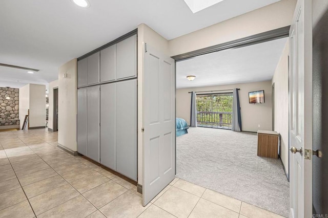 hall with recessed lighting, a skylight, light carpet, and light tile patterned floors