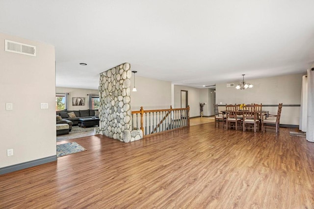 interior space with an inviting chandelier, wood finished floors, and visible vents