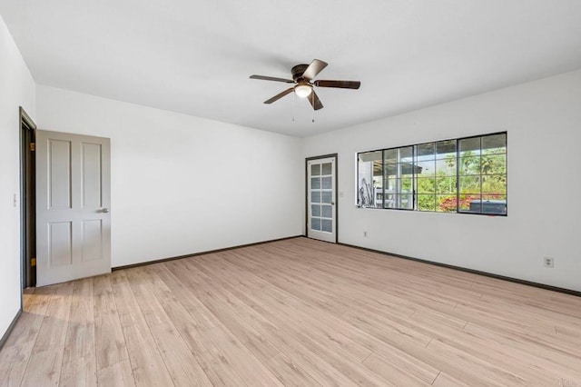 spare room featuring light wood-type flooring, baseboards, and ceiling fan