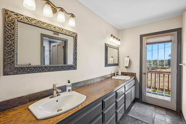 bathroom with double vanity, visible vents, a sink, and stone tile flooring