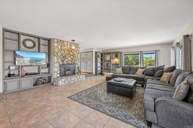 living area with a textured ceiling, tile patterned floors, built in shelves, and a fireplace