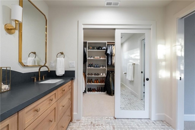 bathroom with a spacious closet, vanity, and visible vents