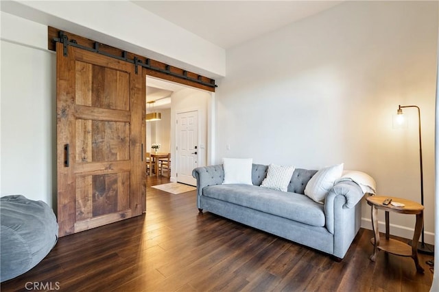 living room featuring a barn door, dark wood-style flooring, and baseboards