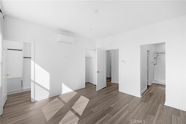 225 Scratch Rd, Covina, CA 91722 - unfurnished bedroom featuring a spacious closet, a wall mounted air conditioner, wood finished floors, a closet, and baseboards
