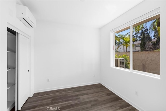 225 Scratch Rd, Covina, CA 91722 - unfurnished bedroom featuring an AC wall unit, dark wood finished floors, baseboards, and a closet