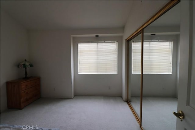 unfurnished bedroom with light colored carpet and a closet