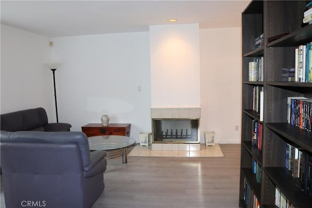 living area with a tiled fireplace, recessed lighting, and wood finished floors