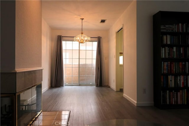 interior space with visible vents, baseboards, wood finished floors, and a notable chandelier