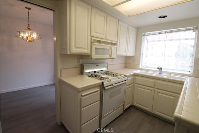 kitchen featuring white appliances, dark wood finished floors, a chandelier, tile countertops, and white cabinetry