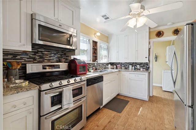 kitchen featuring decorative backsplash, a sink, white cabinets, a ceiling fan, and appliances with stainless steel finishes