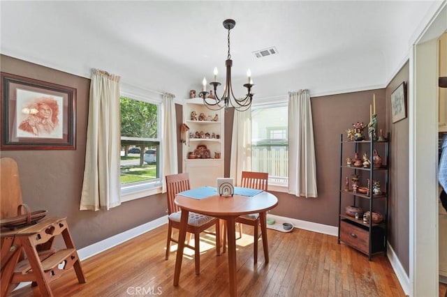 dining area featuring visible vents, wood-type flooring, baseboards, and a chandelier