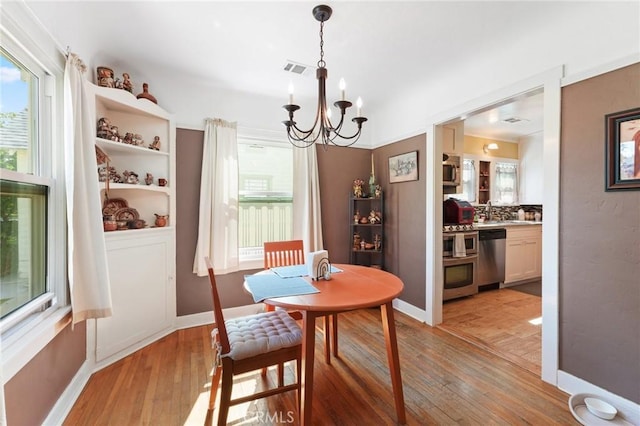 dining area featuring visible vents, baseboards, a chandelier, and light wood finished floors
