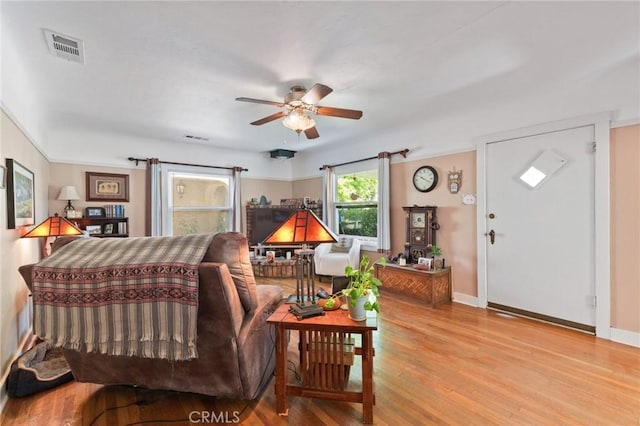 living room with a ceiling fan, baseboards, visible vents, and wood finished floors