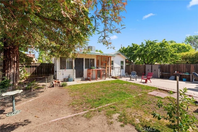 back of house featuring a fenced backyard, a patio area, and a yard