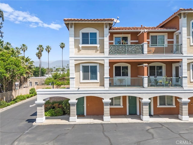 view of front of property featuring a mountain view, a balcony, and stucco siding