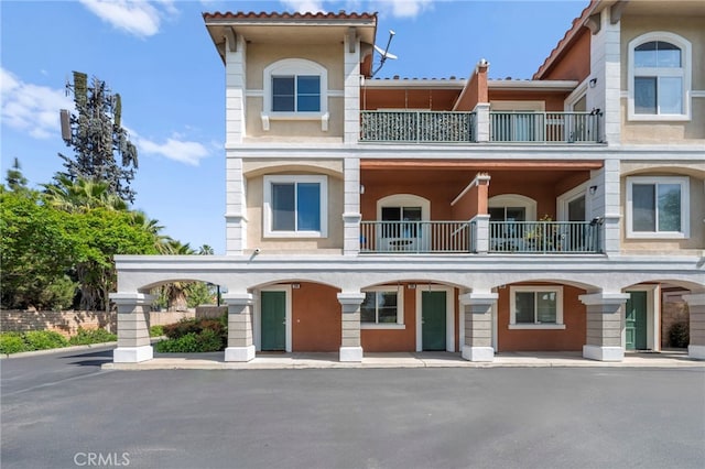 view of front of house with a tiled roof, a balcony, and stucco siding
