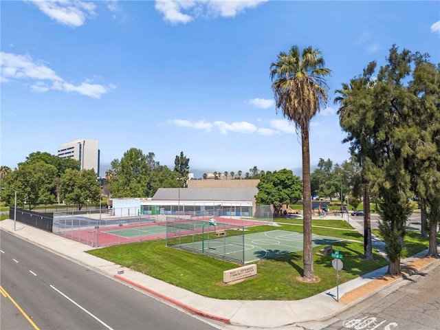 surrounding community with a lawn, a tennis court, and fence