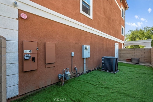 view of side of home with stucco siding, a lawn, and central AC