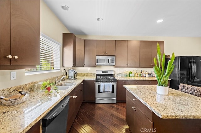 kitchen with a center island, dark wood finished floors, a sink, light stone counters, and black appliances