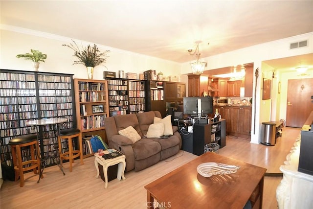 living room with light wood-style flooring, crown molding, and visible vents