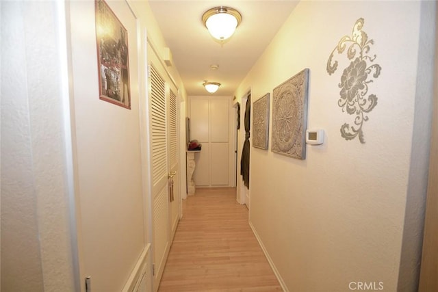 corridor with light wood-style flooring and baseboards