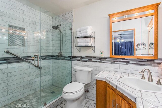 7045 Oak Hill Rd, Oak Hills, CA 92344 - full bathroom with toilet, tile walls, a stall shower, and vanity