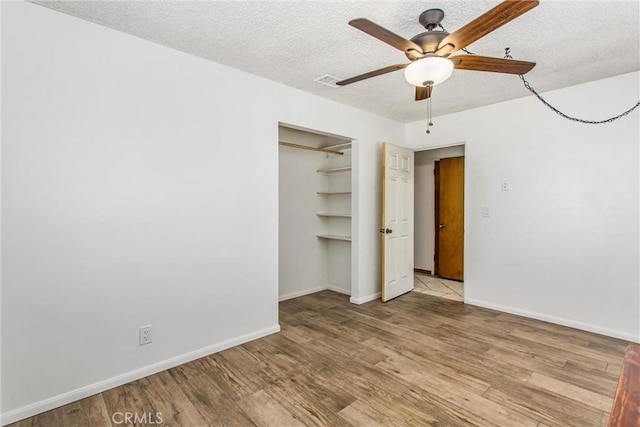 7045 Oak Hill Rd, Oak Hills, CA 92344 - unfurnished bedroom with baseboards, wood finished floors, and a textured ceiling