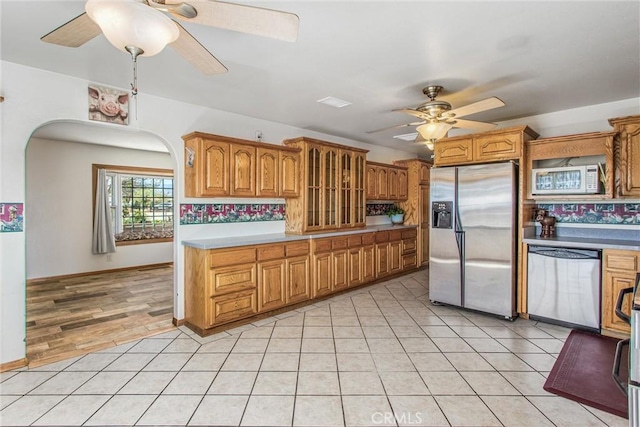 7045 Oak Hill Rd, Oak Hills, CA 92344 - kitchen with brown cabinetry, ceiling fan, appliances with stainless steel finishes, and arched walkways