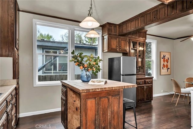 kitchen with dark wood-type flooring, wooden counters, freestanding refrigerator, and baseboards
