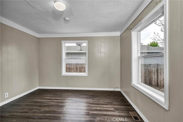 spare room featuring baseboards, a textured ceiling, and dark wood-style floors