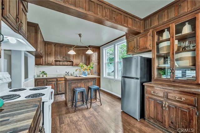kitchen featuring glass insert cabinets, hanging light fixtures, freestanding refrigerator, dark wood-style floors, and electric range