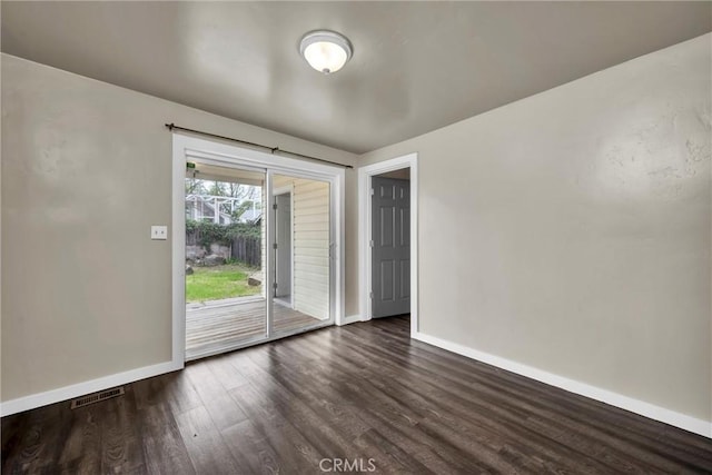 unfurnished room featuring baseboards, dark wood finished floors, and visible vents