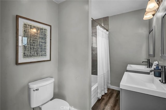 bathroom with shower / bath combination with curtain, vanity, toilet, wood finished floors, and baseboards