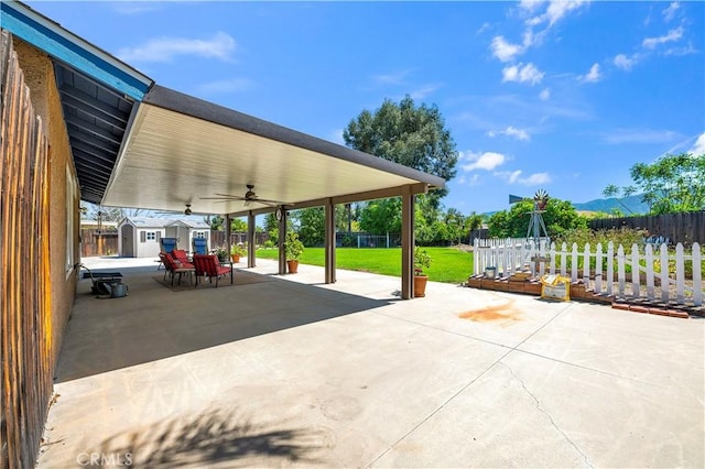 view of patio with a fenced backyard, an outdoor structure, a shed, and ceiling fan