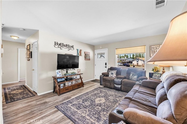 living area with baseboards, wood finished floors, and visible vents