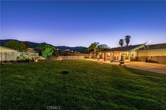 view of yard with a fenced backyard, a mountain view, and a patio area