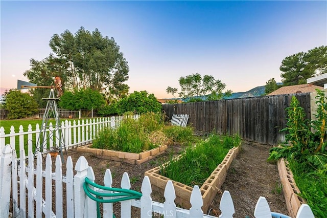 yard at dusk with a fenced backyard and a garden