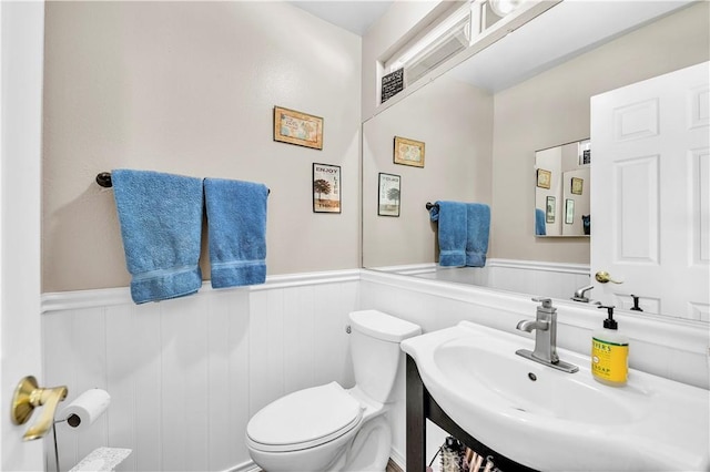 bathroom featuring toilet, vanity, and wainscoting
