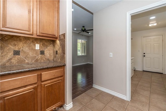 27321 Carlton Oaks St, Murrieta, CA 92562 - kitchen with light tile patterned floors, a ceiling fan, dark stone countertops, baseboards, and backsplash