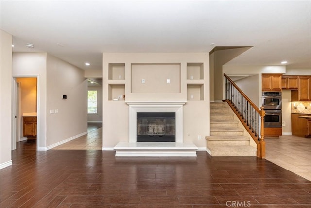 27321 Carlton Oaks St, Murrieta, CA 92562 - unfurnished living room featuring a glass covered fireplace, recessed lighting, stairway, wood finished floors, and baseboards