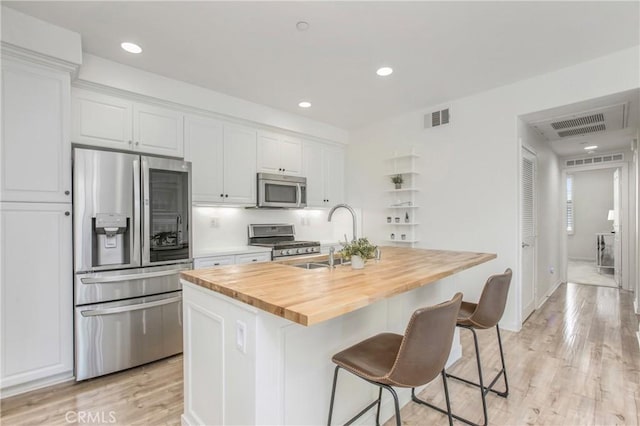 201 Native, Irvine, CA 92618 - kitchen with stainless steel appliances, wooden counters, an island with sink, white cabinetry, and light wood finished floors