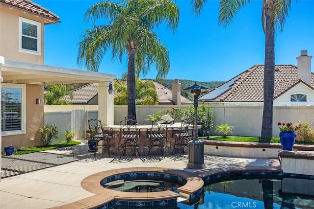 view of patio / terrace featuring outdoor dry bar, a fenced backyard, an in ground hot tub, and an outdoor pool