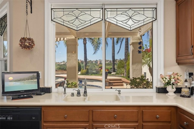 kitchen with dishwasher, brown cabinets, a sink, and light countertops