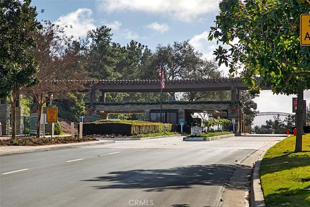 view of road featuring a gated entry and curbs