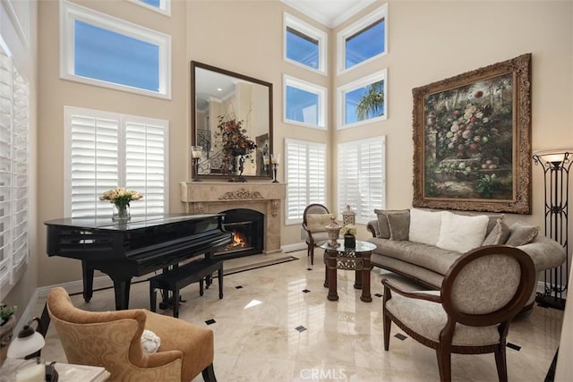 sitting room with a premium fireplace, plenty of natural light, baseboards, and a high ceiling