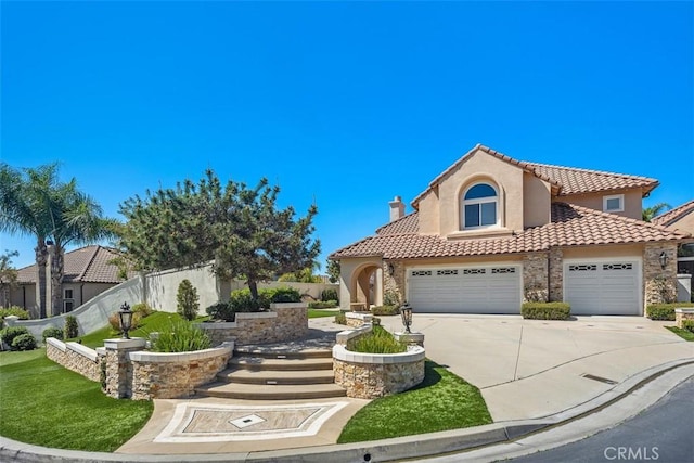 mediterranean / spanish house with a front lawn, a tiled roof, concrete driveway, fence, and stucco siding