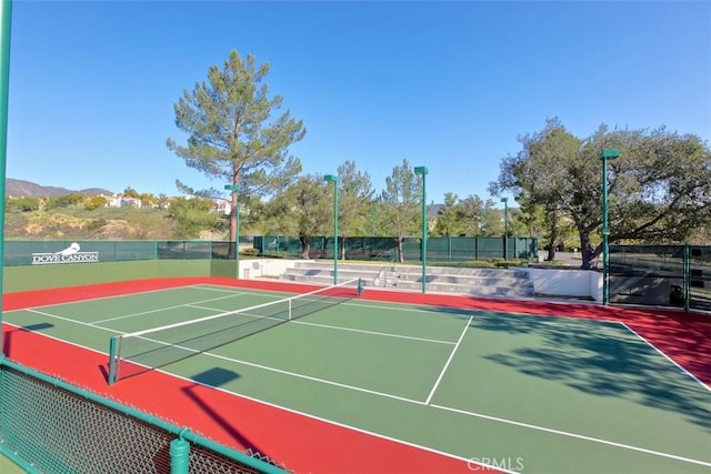 view of tennis court with fence and community basketball court