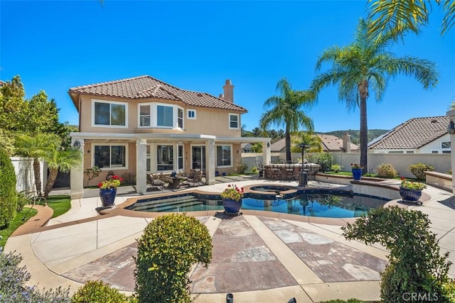 view of swimming pool with a pool with connected hot tub, a patio, and fence